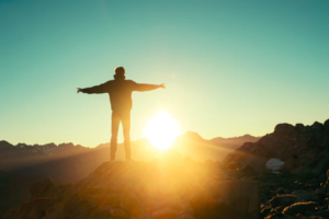 Man on mountain with sun coming up