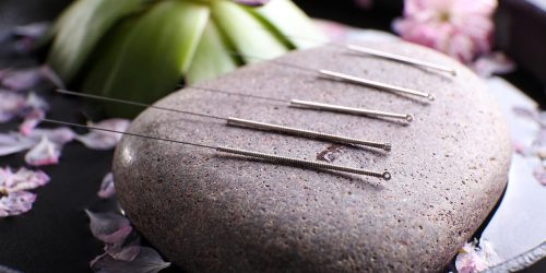 Acupuncture needles with spa stone on tray, closeup